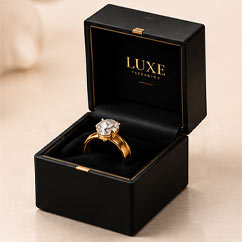 Black jewelry box holding a gold ring